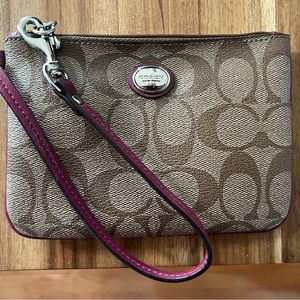 Coach logo print wristlet with berry colored strap.